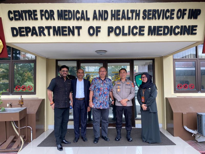Four men standing in front of a building labeled "Centre for Medical and Health Service of INP Department of Police Medicine."